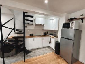 a kitchen with white cabinets and a spiral staircase in it at Charmant duplex proche Paris in Saint-Maurice