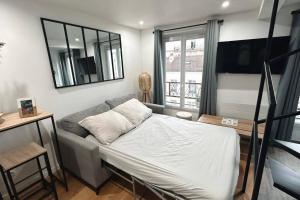 a bedroom with a bed and a couch and a mirror at Charmant duplex proche Paris in Saint-Maurice