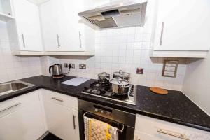 uma cozinha com armários brancos e um forno com placa de fogão em Clarkson Court 1Bedroom Flat em Hatfield