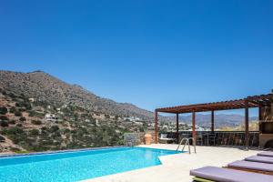 a swimming pool with a mountain in the background at Maris Villas in Elounda