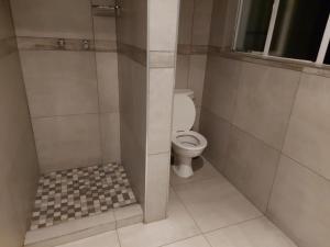 a bathroom with a toilet and a tiled floor at KLOOFIES GUESTHOUSE in Roodepoort
