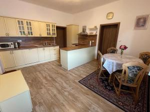 una cocina con mesa y sillas y una cocina con armarios blancos. en Apartmány U sv. Anny en Kadaň