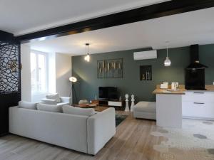 a living room with a white couch and a kitchen at Gîte l'Echappée Belle in Brezolles