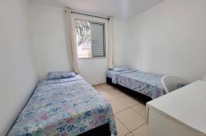 Habitación pequeña con 2 camas y ventana en Condomínio Olhos D'agua en Mauá