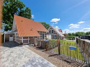 een huis met een oranje dak en een hek bij Ferienhaus im Angerdorf in Cuxhaven