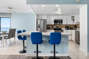 a kitchen with a large island with blue chairs at Luxury Oceanfront Condo/Indoor pool/Massage chair in Ocean City