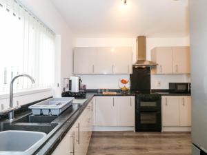 a kitchen with white cabinets and a sink at 28 Wordsworth Avenue in Wigan