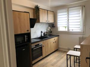 a kitchen with wooden cabinets and a black refrigerator at Camden - Extérieur et parking in Reims