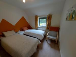 a bedroom with two beds and a chair and a window at La Clé du Circuit Spa-Francorchamps in Stavelot