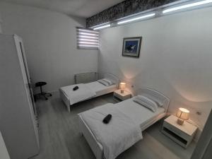 a room with two beds and two tables with lamps at Apartman Marija in Livno