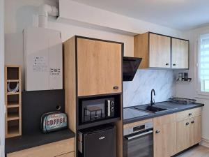 a kitchen with wooden cabinets and a black appliances at Camden - Extérieur et parking in Reims