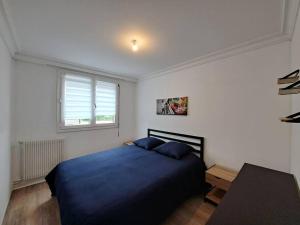 a bedroom with a blue bed and a table at Camden - Extérieur et parking in Reims