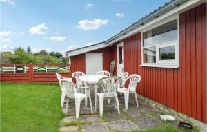 HaslevgårdeにあるAmazing Home In Hadsund With 3 Bedroomsの赤い家の隣のパティオ(テーブル、椅子付)