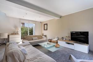 a living room with a couch and a flat screen tv at Bright pearl with garden near the sea in Hyères