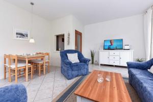 sala de estar con sofá azul y mesa en Ferienwohnung Bensersiel Ahoi en Bensersiel