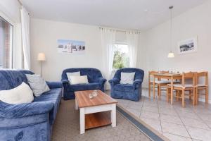 a living room with two blue chairs and a table at Ferienwohnung Bensersiel Ahoi in Bensersiel