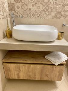baño con bañera blanca en una estantería de madera. en Sabea Guest House, en Melissano