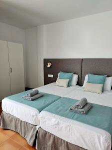 1 dormitorio con 2 camas grandes y toallas. en Apartamentos La Cebada, en Morro del Jable