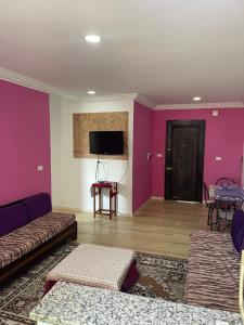 cosy Furnished appartment في الزهراء: غرفة معيشة مع جدران أرجوانية وأريكة