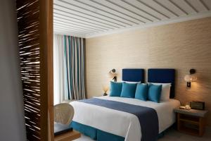 a bedroom with a large bed with blue pillows at Summer Senses Luxury Resort in Logaras