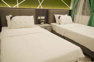 2 Betten in einem Zimmer mit weißer Bettwäsche und Kissen in der Unterkunft 38 villa homestay in Muar