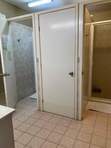 uma casa de banho com um chuveiro e uma porta branca em Adalong Student Guest House em Brisbane