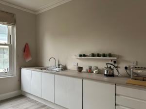 kuchnia z białymi szafkami i zlewem w obiekcie Strawberry Dale Apartment w mieście Harrogate