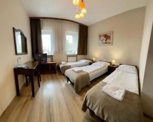 ラシンにあるHotelik Koronaのベッド2台とデスクが備わるホテルルームです。