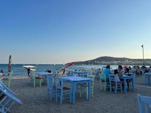 a group of people sitting at tables on the beach at Ruby’s Apartment 5 min to the sea in Vari