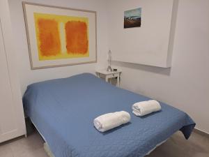 una camera da letto con un letto blu con due asciugamani di סטודיו במרכז מודיעין a Modi'in-Maccabim-Re'ut