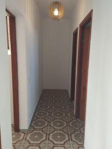un corridoio vuoto con pavimento piastrellato e lampadario pendente. di Vivienda vacacional a Mocanal