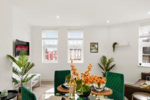 ein Wohnzimmer mit einem Tisch und grünen Stühlen in der Unterkunft Livestay-Modern One and Two Bed Apartments in Burnt Oak London in Edgware