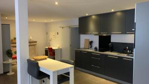 una cocina con armarios negros y una mesa blanca en Ruime studio in Deurne, en Amberes