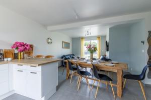 cocina y comedor con mesa de madera y sillas en Les Fuchsias - Maison proche de la mer, en Asnelles