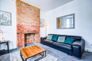 a living room with a leather couch and a brick fireplace at Pass the Keys Beautiful large modern house in Southend in Southend-on-Sea