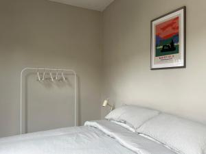a white bedroom with a bed and a picture on the wall at Strawberry Dale Apartment in Harrogate