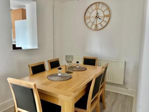 a dining room table with chairs and a clock on the wall at Executive 3 bedroom Port Talbot Town Centre Margam Sleeps 7 in Taibach