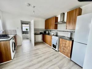 uma cozinha com electrodomésticos brancos e armários de madeira em Executive 3 bedroom Port Talbot Town Centre Margam Sleeps 7 em Taibach
