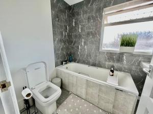 a bathroom with a toilet and a tub and a sink at Executive 3 bedroom Port Talbot Town Centre Margam Sleeps 7 in Taibach