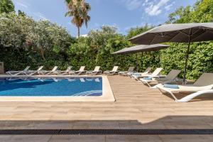 a pool with lounge chairs and an umbrella at Villa Diagonal in Can Picafort