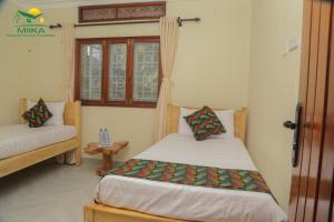 a bedroom with a bed and a window at Miika Guest House in Entebbe