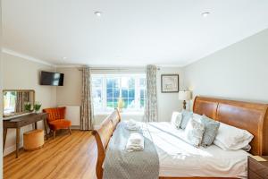 a bedroom with a bed and a desk and a window at Sparrowhawk Cottage with Hot Tub in Newton Stewart