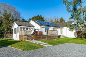 a white house with solar panels on it at Sparrowhawk Cottage with Hot Tub in Newton Stewart