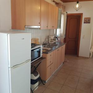 a kitchen with wooden cabinets and a white refrigerator at Andrianas Apartment in Áyios Pétros +5 photos