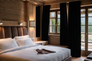 a bedroom with a large white bed and windows at Rosapetra SPA Resort - Small Luxury Hotels of the World in Cortina dʼAmpezzo