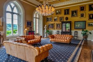 een woonkamer met lederen meubels en een kroonluchter bij Finest Retreats - Apley Hall in Bridgnorth