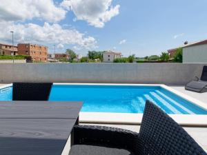 a swimming pool with chairs and a table on a patio at Villa Kana in Umag