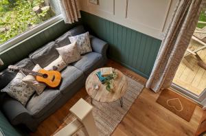 a living room with a couch and a guitar at Extraordinary Huts Ltd in Rye