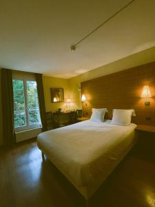 een slaapkamer met een groot bed met witte kussens bij Hostellerie Du Lys in Lamorlaye