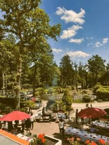 Hostellerie Du Lys في Lamorlaye: حديقة بها طاولات ومظلات في الحديقة